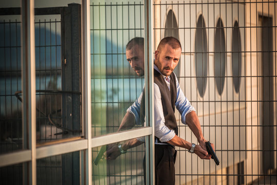 Man in business attire poised behind corner with handgun, Cagliari, Sardinia, Italy