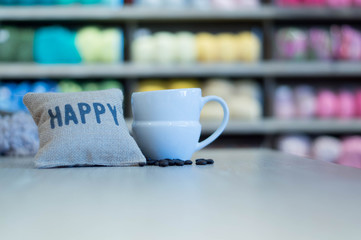 Cup of coffee with beans with blurred yarns stack background