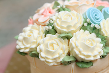 Wedding or birthday cake decorated with flowers made from cream,