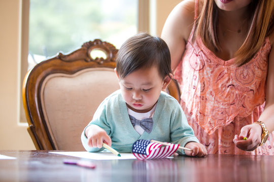 Baby boy with American flag, crayon drawing at dining room table