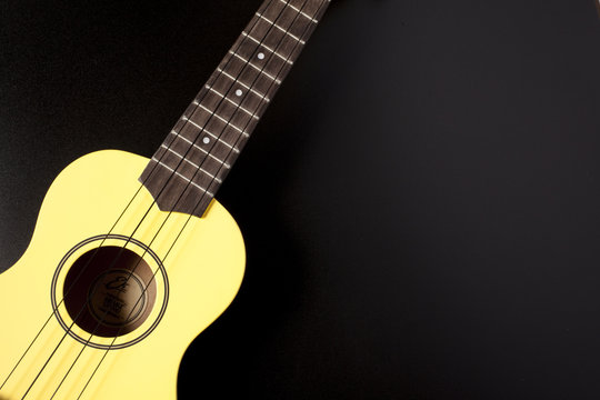 yellow ukulele on black background