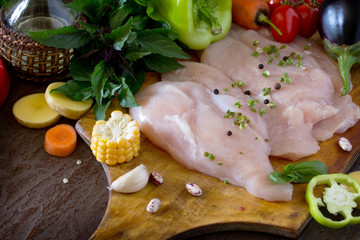 Fresh raw chicken with vegetables on a cutting board.