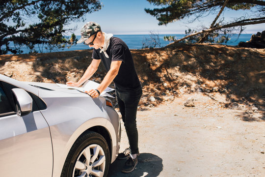 Man On Road Trip Reading Map On Car Hood, Big Sur, California, USA