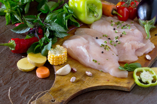 Fresh raw chicken with vegetables on a cutting board.