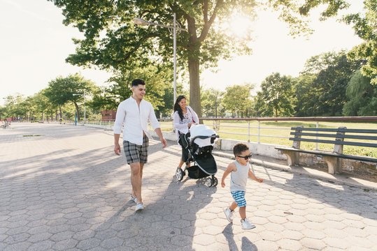 Parents walking with pushchair and toddler son at Pelham Bay Park, Bronx, New York, USA