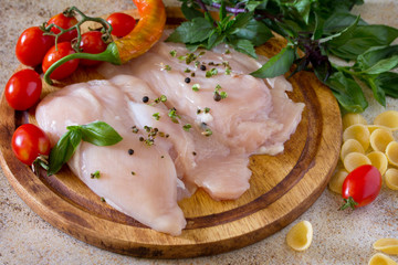 Raw chicken with pasta shells and tomato on brown stone backgrou