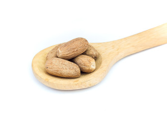 Nutmeg on wooden spoon over white background.