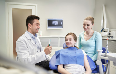 Obraz premium happy dentist showing toothbrush to patient girl