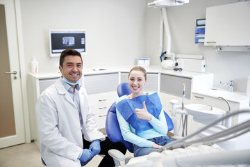 Obraz premium happy male dentist with woman patient at clinic