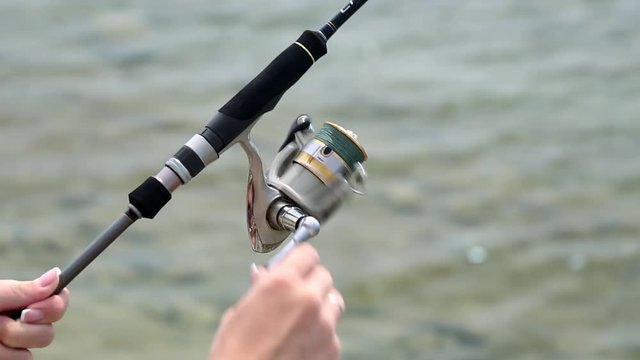 Spinning Reel. Sea fishing. A man fishing on the coast. Fisherman with spinning. The hand rotates the reel spinning.