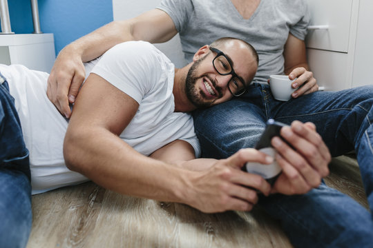 Gay couple sitting on floor, taking selfie