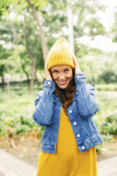 Portrait of smiling young woman putting on yellow cap