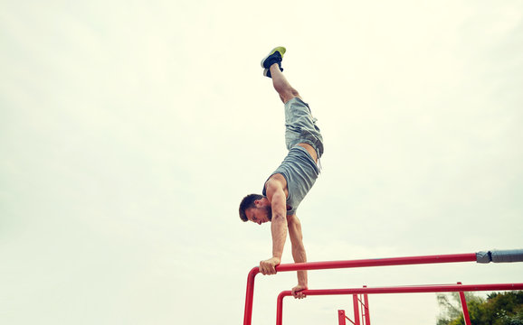 young man exercising on parallel bars outdoors