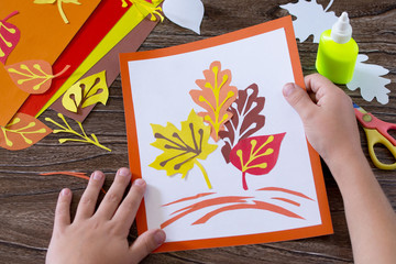 Autumn leaves of colored paper on a wooden background. Sheets of