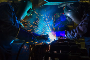 Workers are welding automotive part in factory