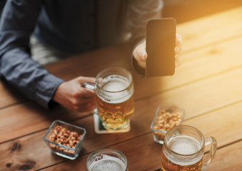 close up of friends with smartphone and beer