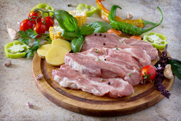 Fresh raw meat pork tenderloin with vegetables on a cutting boar