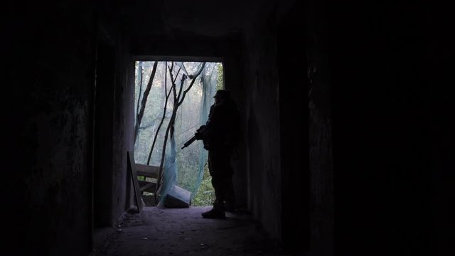 The military is in a dark hallway. Silhouette of a soldier with a machine gun in the building