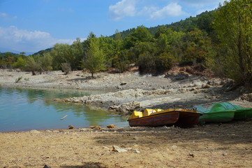 Abandoned old boats on the rocky shore of a lake at the edge of a forest