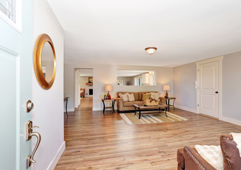 Open floor plan living room interior in white tones with hardwood floor.