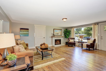 Open floor plan living room interior in white tones with hardwood floor.