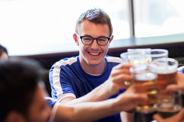 football fans clinking beer glasses at sport bar