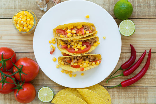 Colorful mexican tacos cooked with crispy taco shells, yellow corn, red tomato and chicken mince