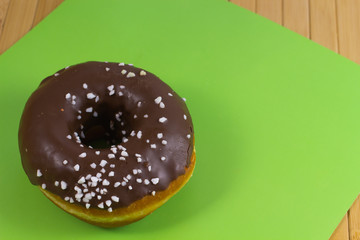 Donut with chocolate icing on a green background