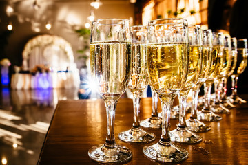 A lot of wine glasses with a cool delicious champagne or white wine at the bar. Alcohol background.