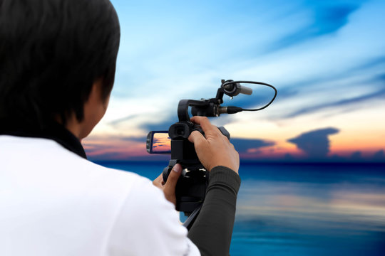 Man recording sunset on the ocean with vedio recorder