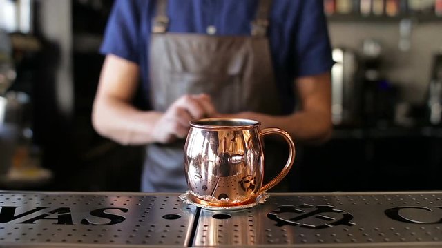 The bartender pours the ice in a copper bowl