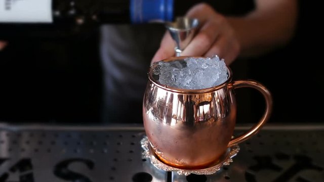 The bartender makes a cocktail in a copper cup