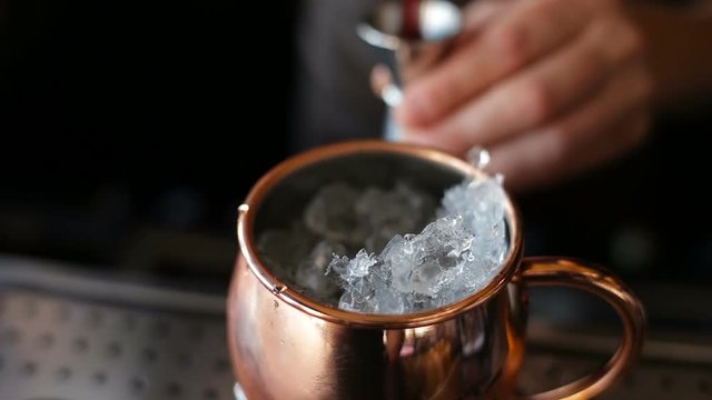 The bartender makes a cocktail in a copper bowl