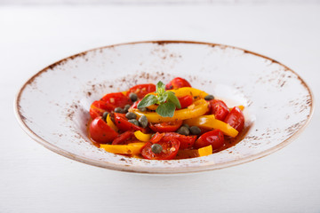 Warm salad with cherry tomatoes,sweet peppers and capers.selective focus.