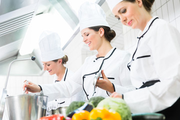 Team von Köchinnen beim Zubereiten von Gerichten in einer Kantinen-Küche