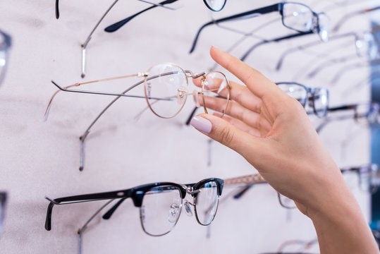 Frau greift nach Brille im Regal beim Optiker, Makro auf die Hand