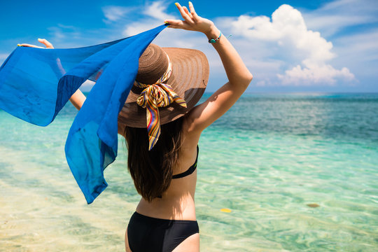 Touristin mit blauem Seidenschal an tropischem Strand macht Urlaub