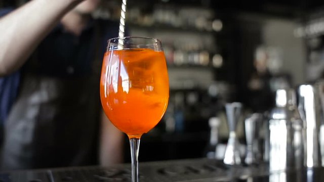 The bartender mixes the ingredients in the glass. Sticks and cocktail straws into the glass.