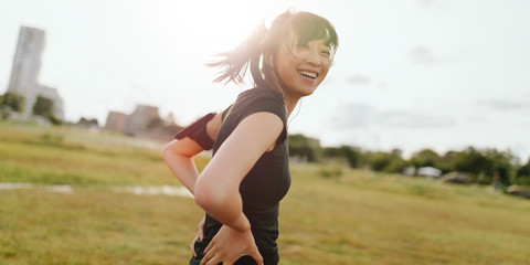 Female runner laughing on field in morning