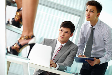 Two businessmen staring at beautiful female legs