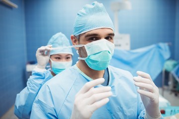 Nurse helping a surgeon in tying surgical mask