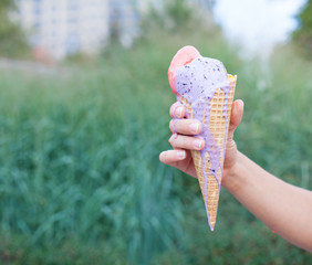 Beautiful woman's hand holding a colorful ice-cream cone. Close up. Outdoor. Summer time