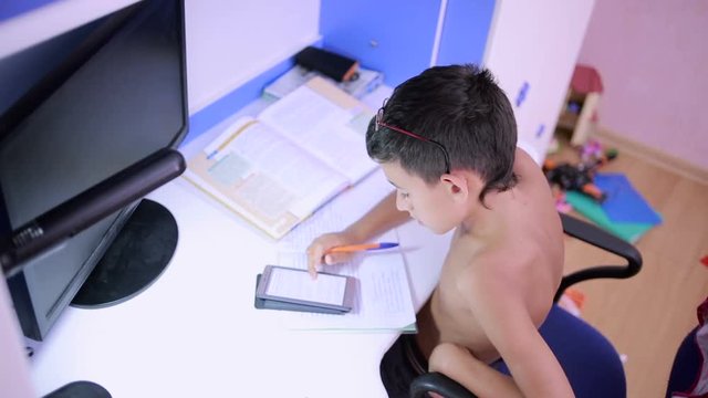 Teenage boy doing homework using a cell phone. natural video
