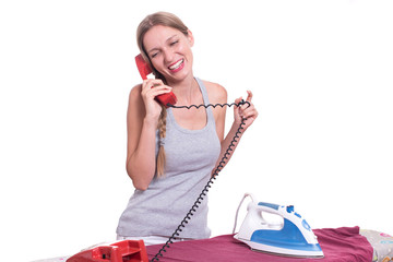 Young woman talking on the phone while ironing clothes