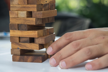 Close-up of asian business man's hand playing wood blocks stack