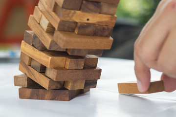 Collapse motion of wood blocks stack game after a man's hand pla