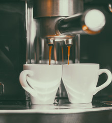 Fresh coffee prepared in the coffee machine. Espresso in small white cups.