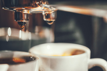 Fresh coffee prepared in the coffee machine. Espresso in small white cups.Close-up of drops of coffee.