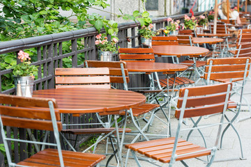 round wooden tables with chairs at summer open air cafe terrace