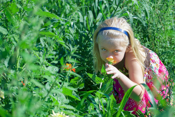 young girl smelling flowers in field
